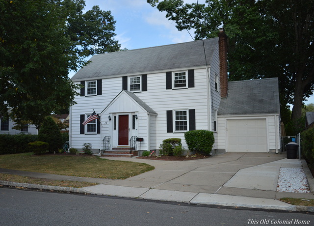 White colonial house with black shutters and red door 